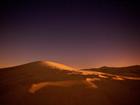 Sand dune after sunset against starry sky